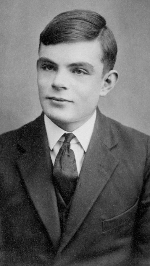 Alan Turing, de terno, olhando de lado