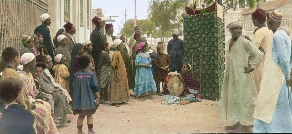 أطفال ورجال يحضرون عرضاً للأراجوز في الشارع عام 1910