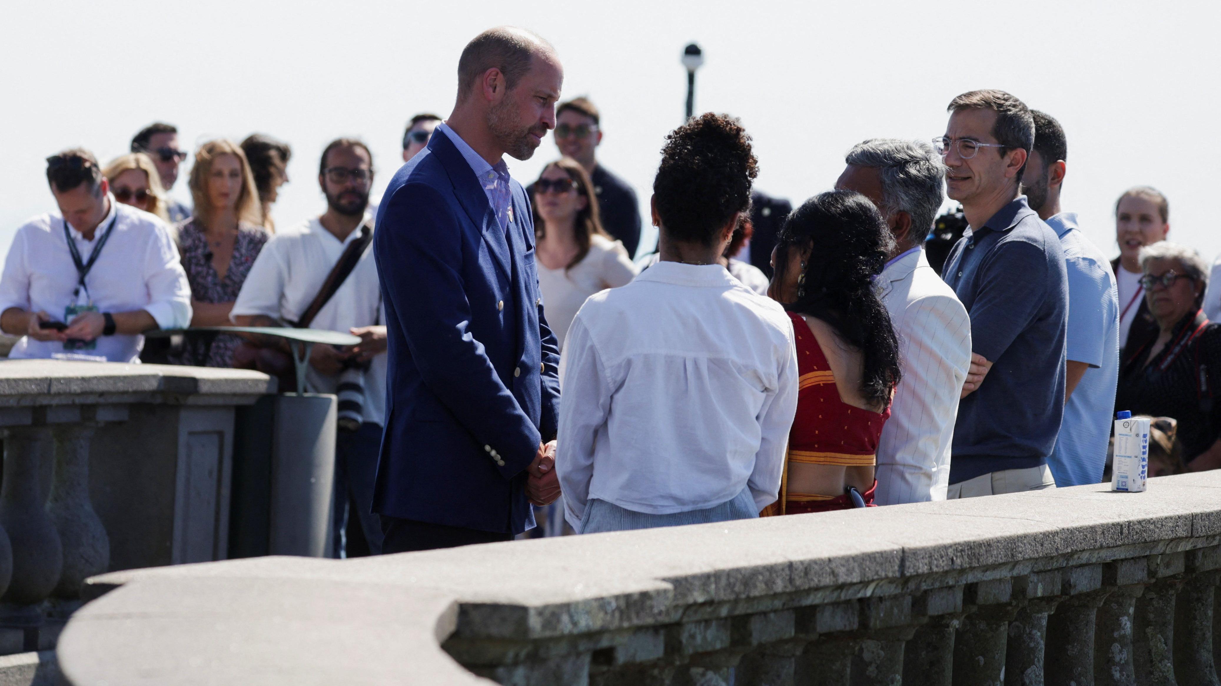 William conversando com um grupo de pessoas. Ao fundo, v&aacute;rias pessoas olhando