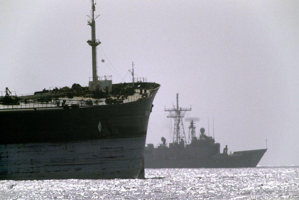 سفينة حربية أمريكية في الخلفية تبحر بجانب سفينة شحن خلال عملية إرنست ويل في مضيق هرمز.