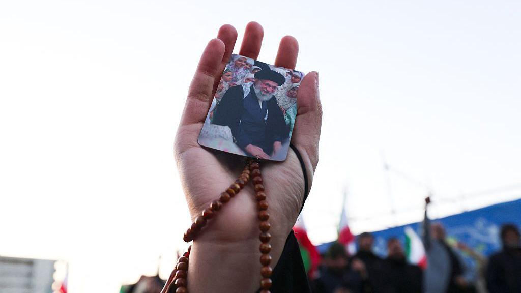 ایک شخص نے ہاتھ میں آیت اللہ علی خامنہ ای کی تصویر اٹھا رکھی ہے