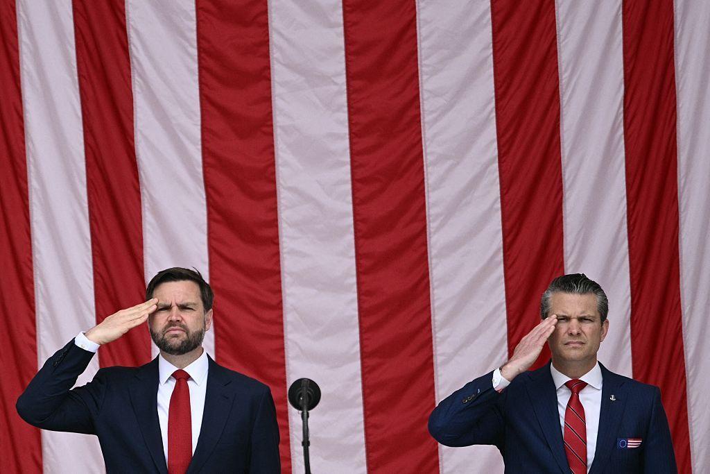 Pete Hegseth (der.) y JD Vance (izq.) en un saludo militar con la bandera de EE.UU. en el fondo