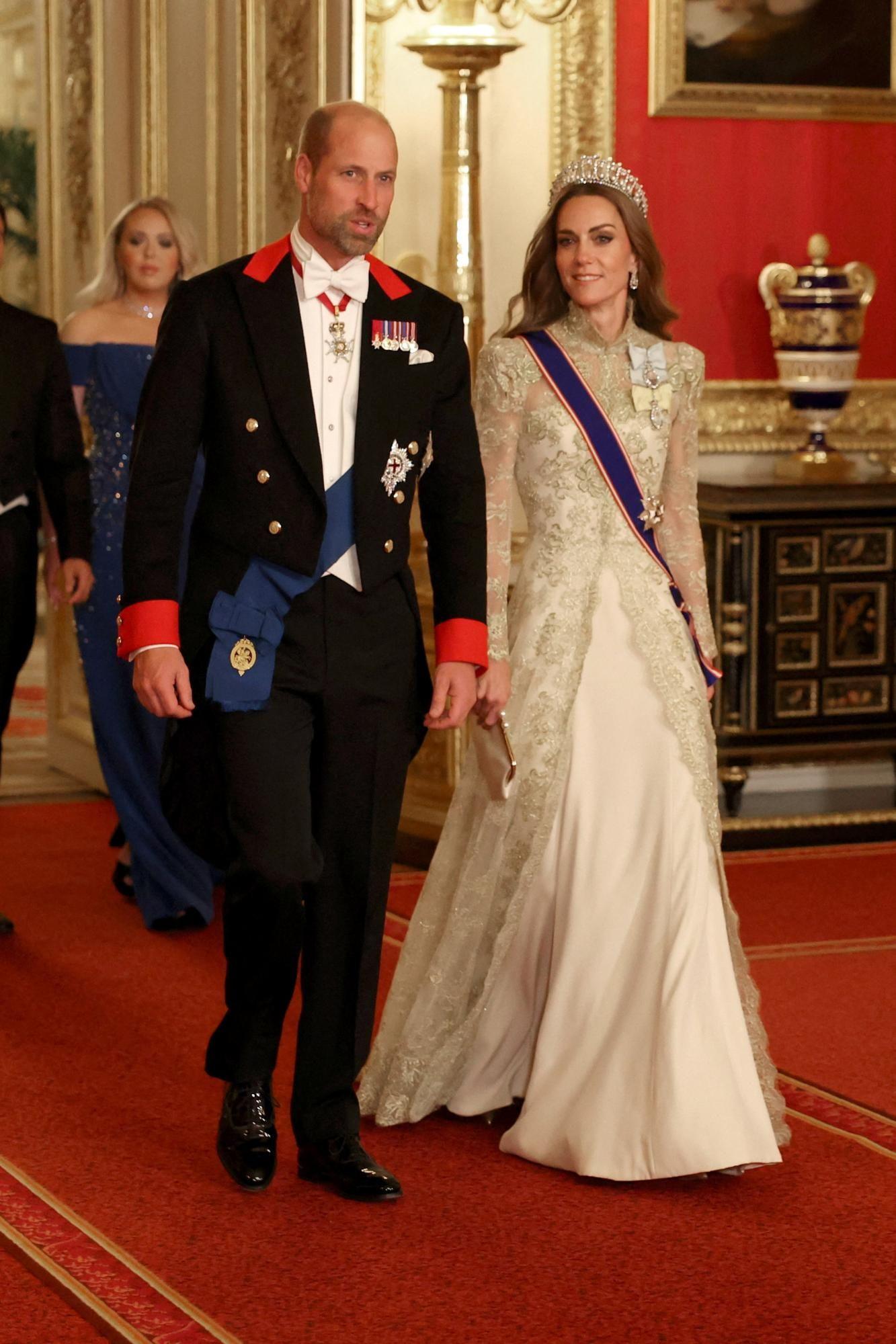 Princ od Velsa nosio je frak, ukrašen kraljevskim ordenjima i oznakama. Sakо su krasili crveni detalji.
Princeza od Velsa nosila je haljinu dizajnerke Filip Lepli, uz dugački plašt od ručno vezene zlatne čipke. Na glavi je imala tijaru Laver Not