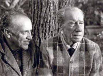 Dos hombres mayores, vestidos casualmente, sentados frente a un árbol
