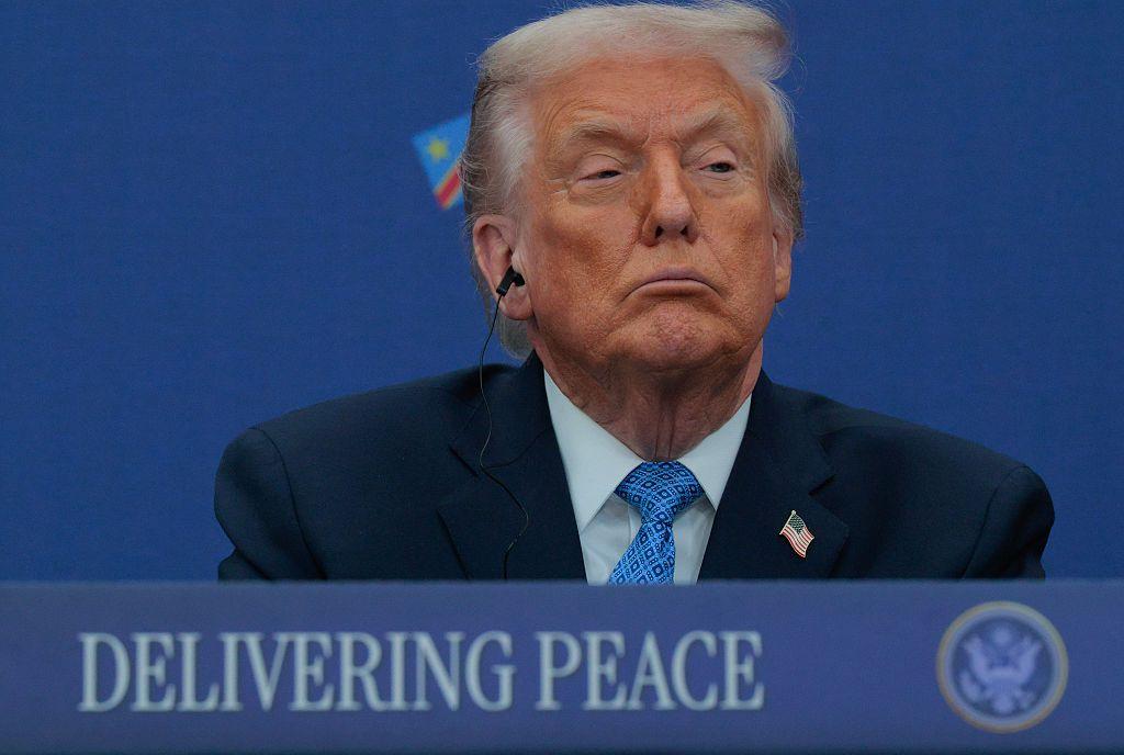Trump, sobre un rótulo con el mensaje "delivering peace" ("entregando paz).