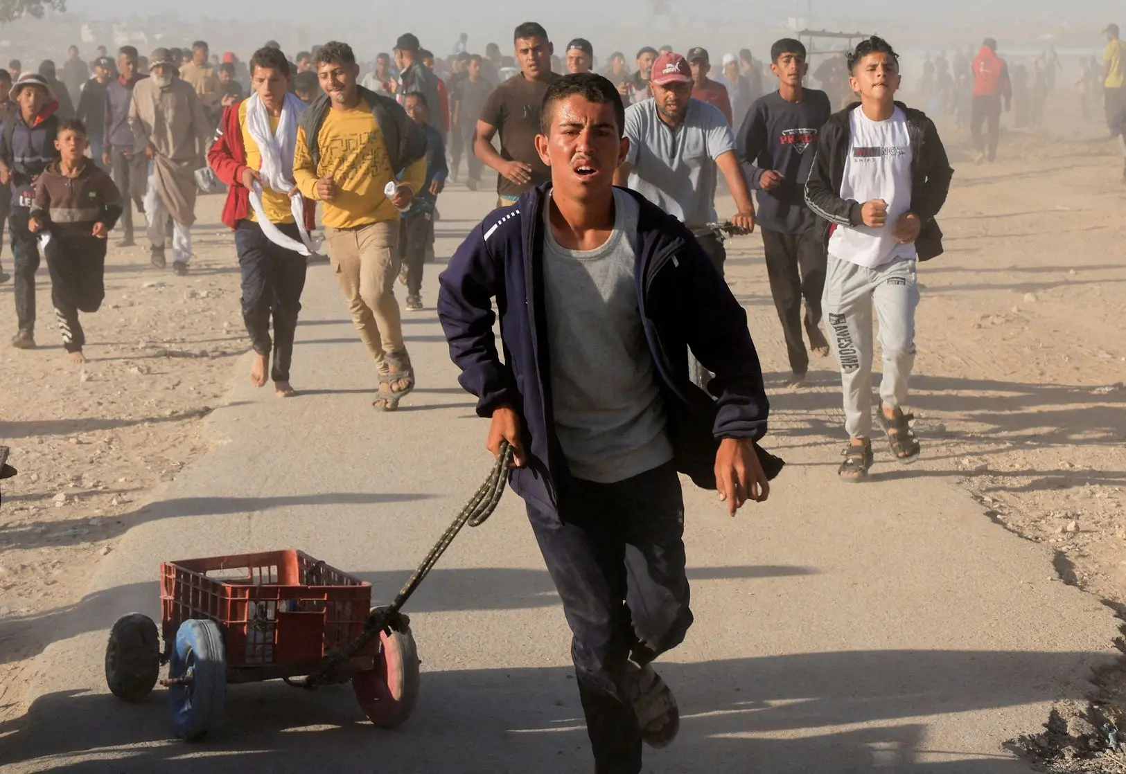 صورة لفلسطيني يجرّ عربة صغيرة باتجاه موقع توزيع مساعدات في قطاع غزة.