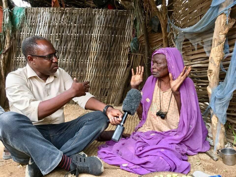 محمد عثمان يتحدث مع سيدة نازحة في مخيم زمزم