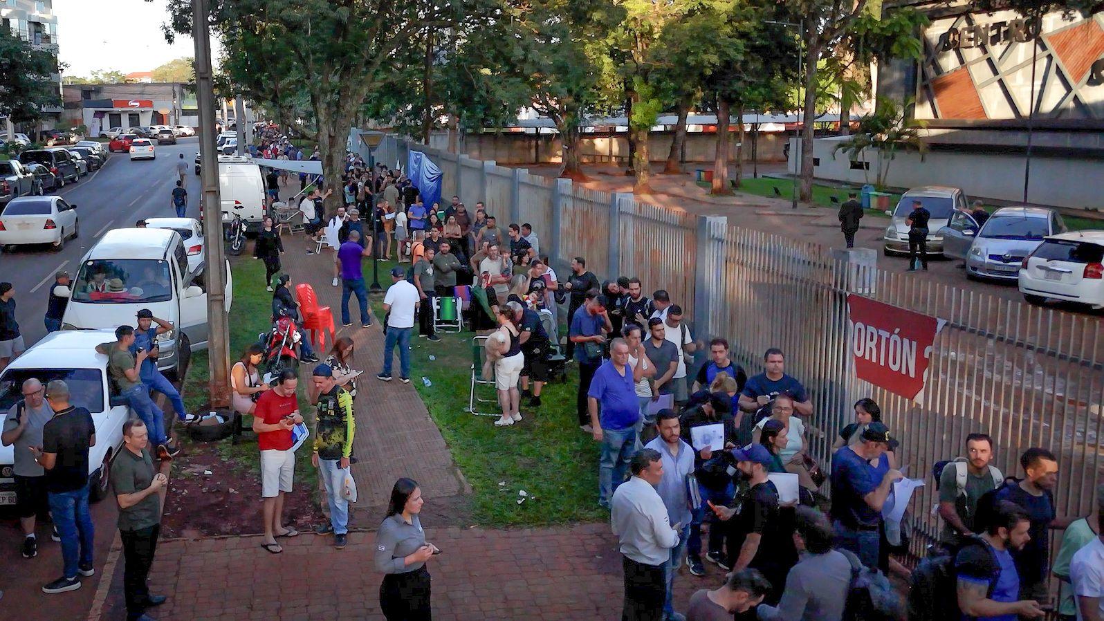 Vista a&eacute;rea de fila cheia de pessoas na porta de pr&eacute;dio p&uacute;blico