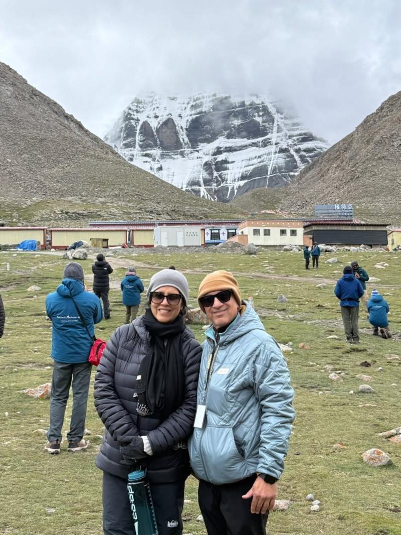 Deepak y Madhu Ahuja cerca del Monte Kailash. Ambos están fuertemente abrigados frente a una montaña nevada. 