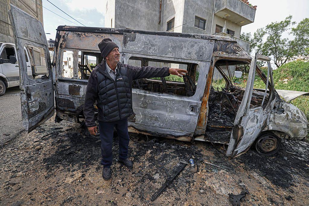 Un hombre junto a un vehículo incendiado en Jalud