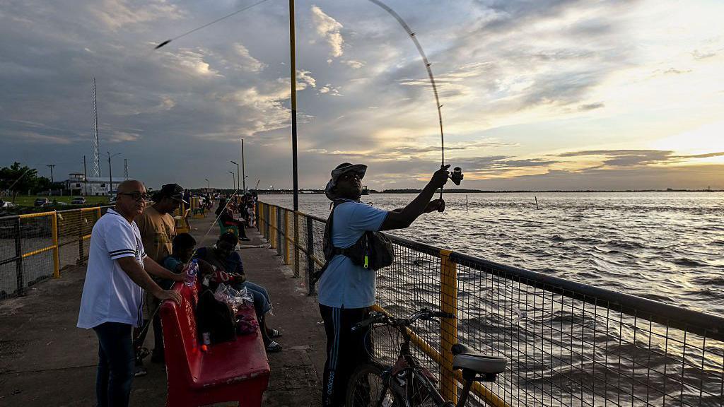 Personas pescando en un muelle de Georgetown, Guyana.