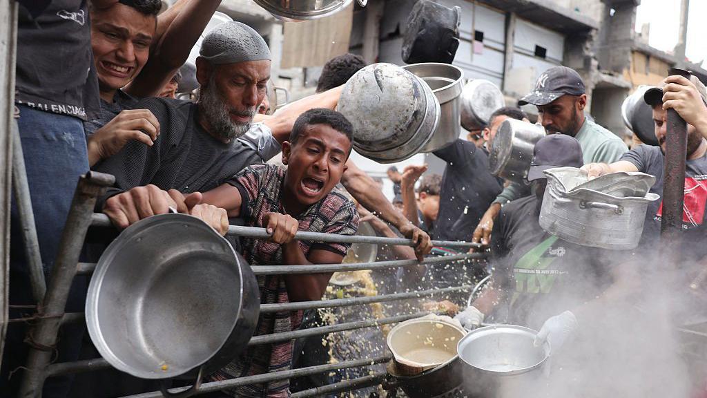 صورة من أعلى - فلسطينيون يكافحون للحصول على حصصهم الغذائية خارج مركز توزيع مكتظ في بيت لاهيا شمال قطاع غزة، في 15 مايو/أيار 2025. 