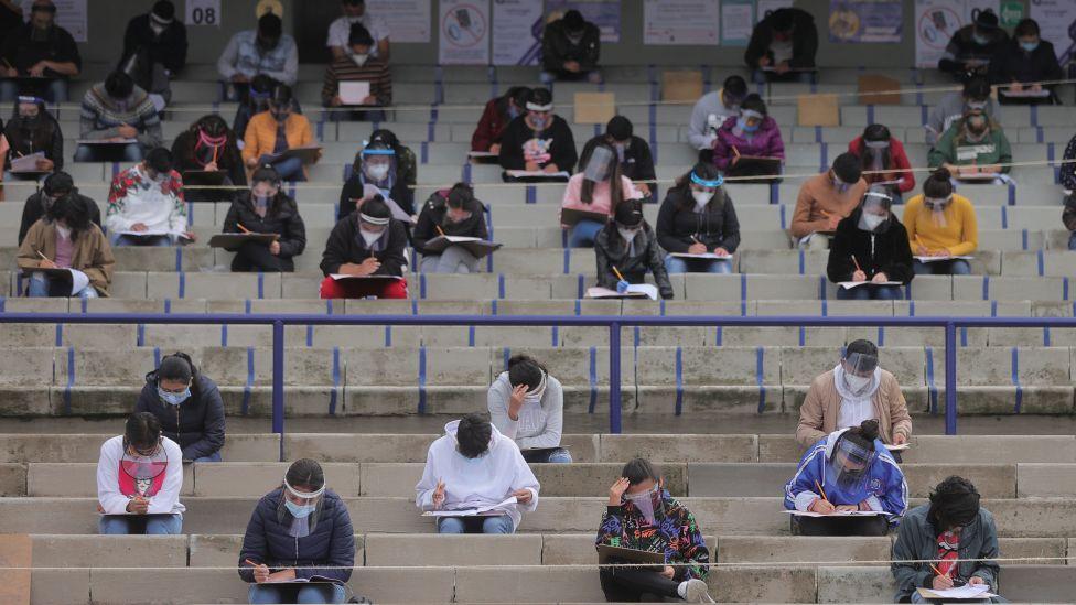 Un grupo de estudiantes realiza un examen durante la pandemia en un auditorio. Tienen mascarillas puestas. 