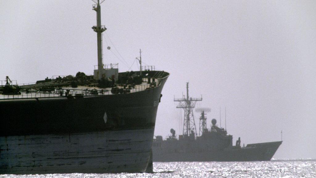 Američki ratni brod u pozadini putuje pored teretnog broda tokom operacije 'Iskrena namera' u Ormuskom moreuzu.