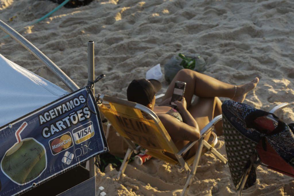 Una persona sentada junto a un quiosco de playa —donde se acepta el sistema de pago instantáneo Pix— en la playa de Ipanema, en Río de Janeiro, Brasil, el 3 de mayo de 2024.