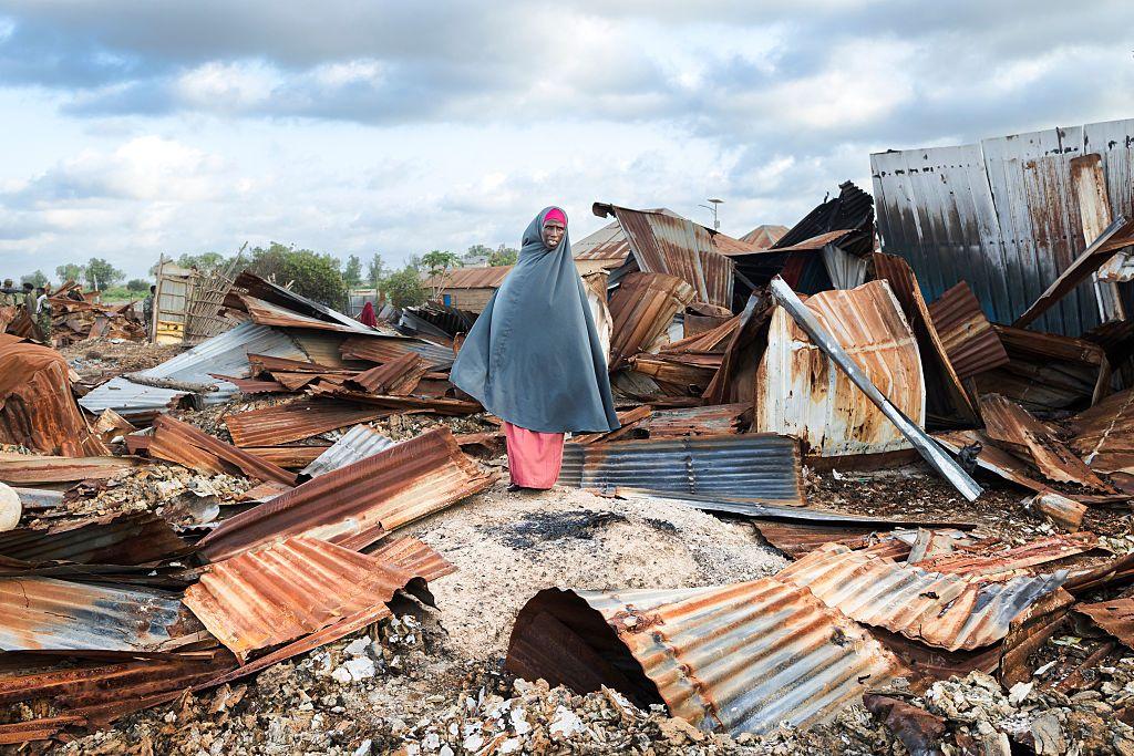 Una mujer sobre chapas rectangulares oxidadas de las que se suelen utilizar para construir viviendas precarias, en Awdheegle, Somalia. 