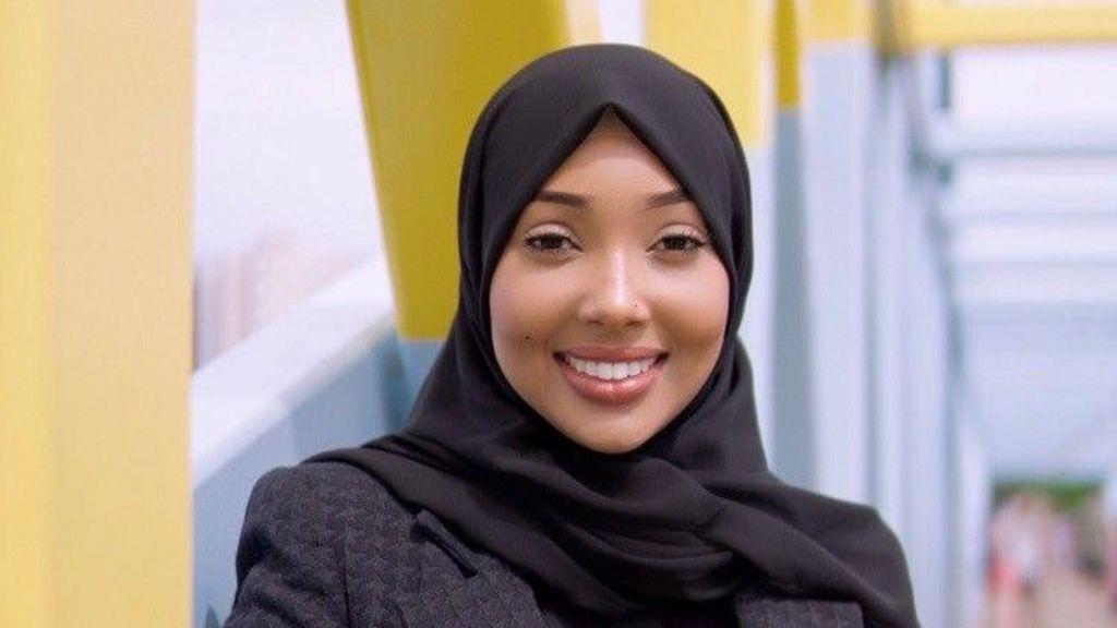 كوثر محمد مواطنة أمريكية صومالية، ترتدي سترة سوداء وحجاباً أسود.