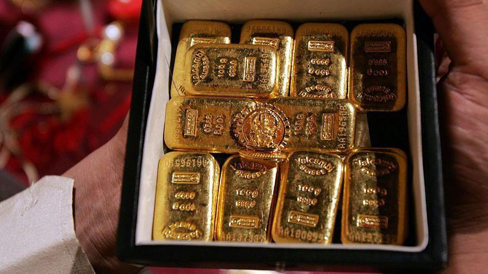 Alguien sostiene una caja de lingotes de oro 