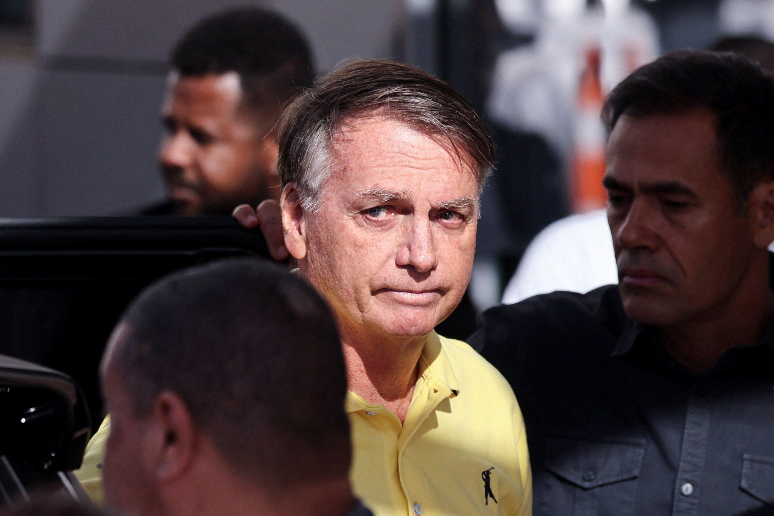 Jair Bolsonaro, de camisa amarela olhando para o lado 