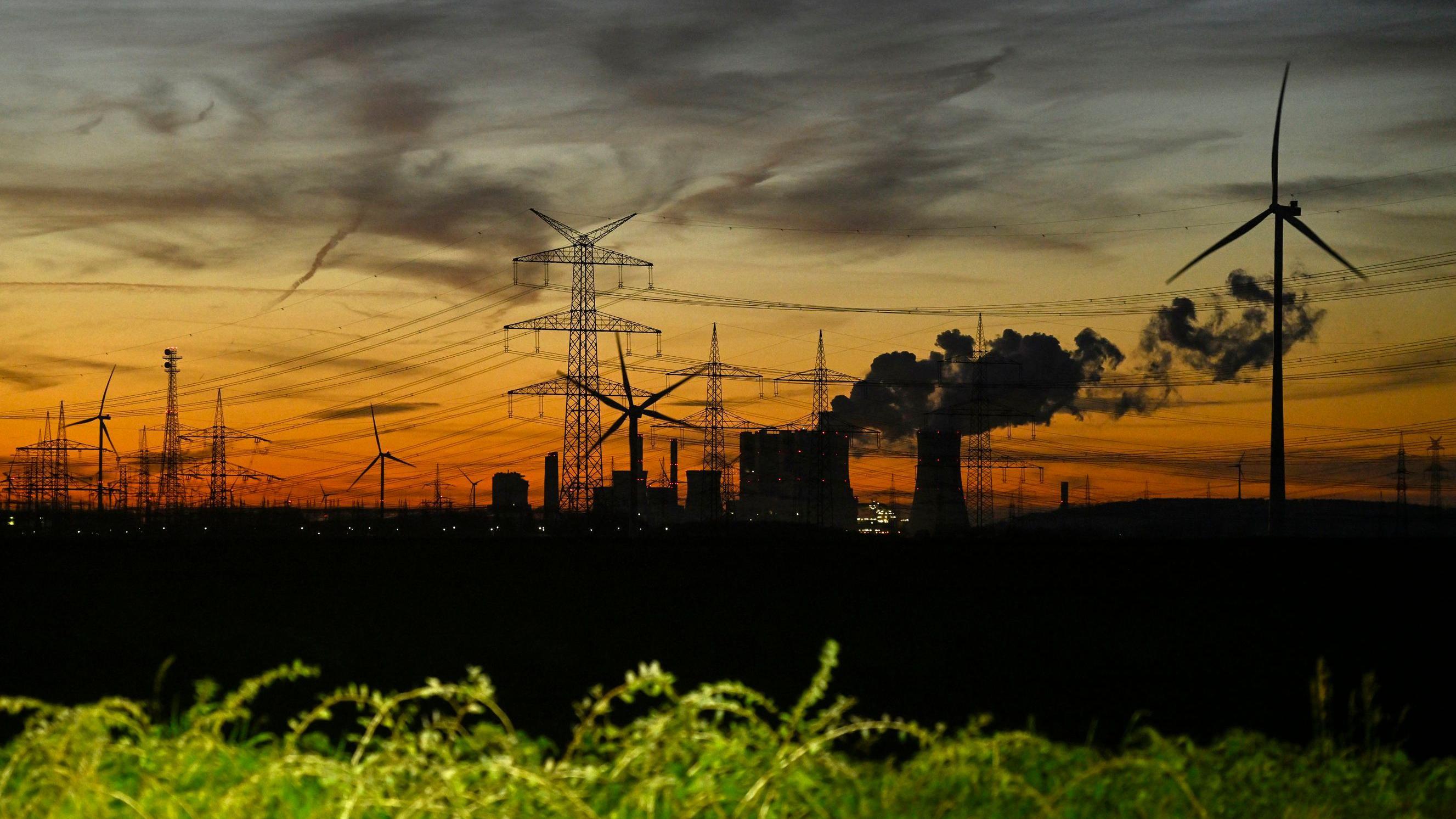 توربينات الرياح وأعمدة الكهرباء بينما تتصاعد الأبخرة من أبراج التبريد في محطة الطاقة التي تعمل بالفحم البني، والتي تديرها شركة الطاقة الألمانية العملاقة RWE بالقرب من نيوراث، غرب ألمانيا. 