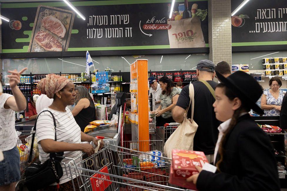 Varias personas en un supermercado con productos