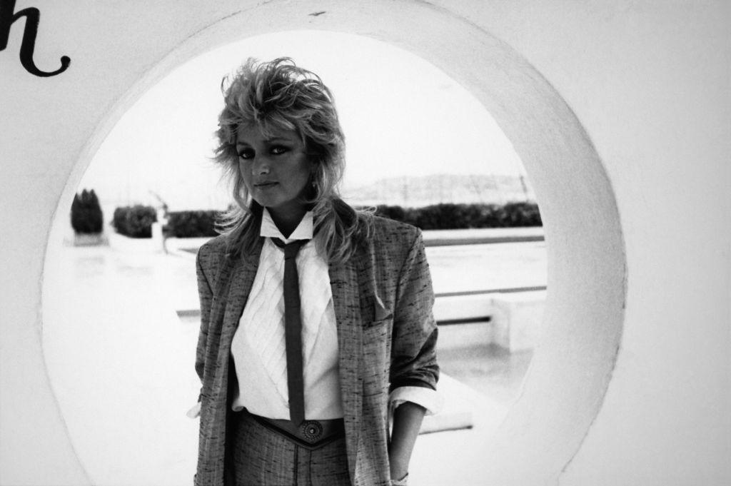 Una foto en blanco y negro de Bonnie Tyler, vestida con un traje, camisa y corbata