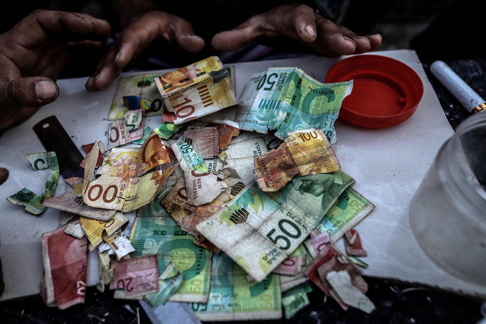 Palestinians repair old and worn-out banknotes as the enclave runs out of hard currency on June 02, 2025, in Gaza City