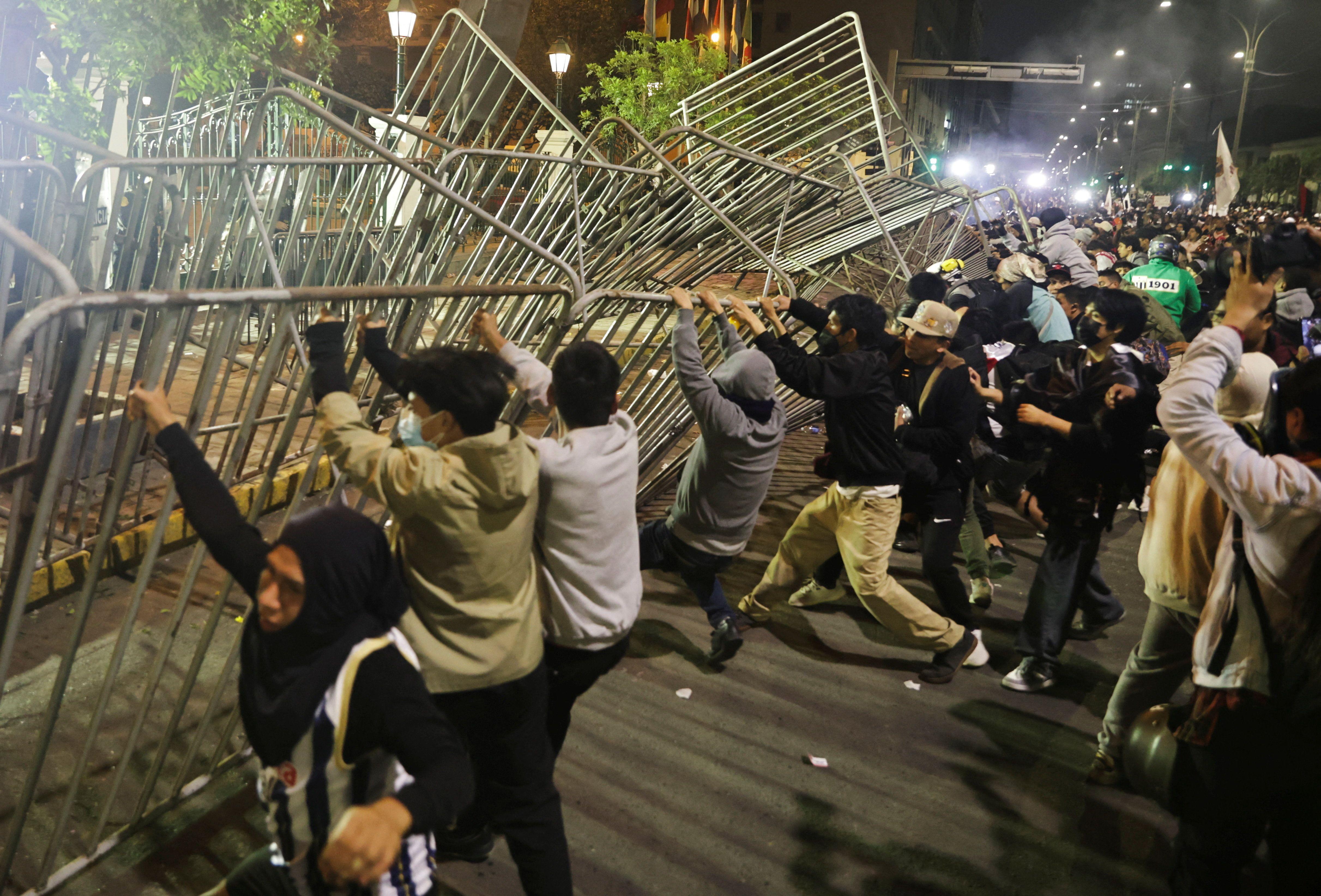 Una multitud de manifestantes trata de quitar las vallas metálicas que les impiden avanzar hacia la sede del Congreso peruano. 
