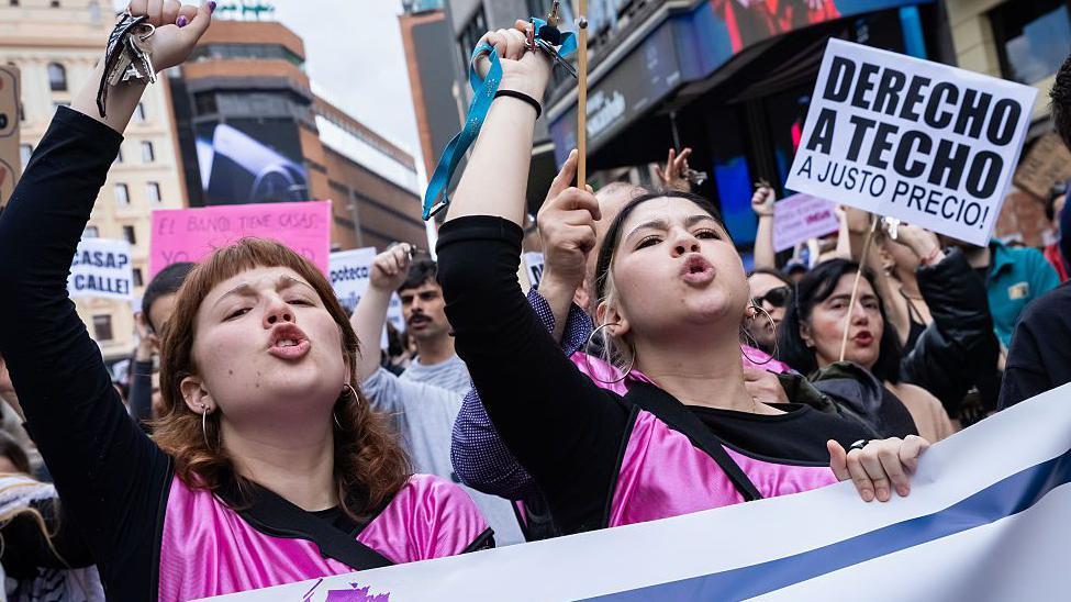 Manifestantes gritan y muestran un cartel con el mensaje "derecho a techo a un justo precio" en una protesta contra el coste de la vivienda en Madrid. 