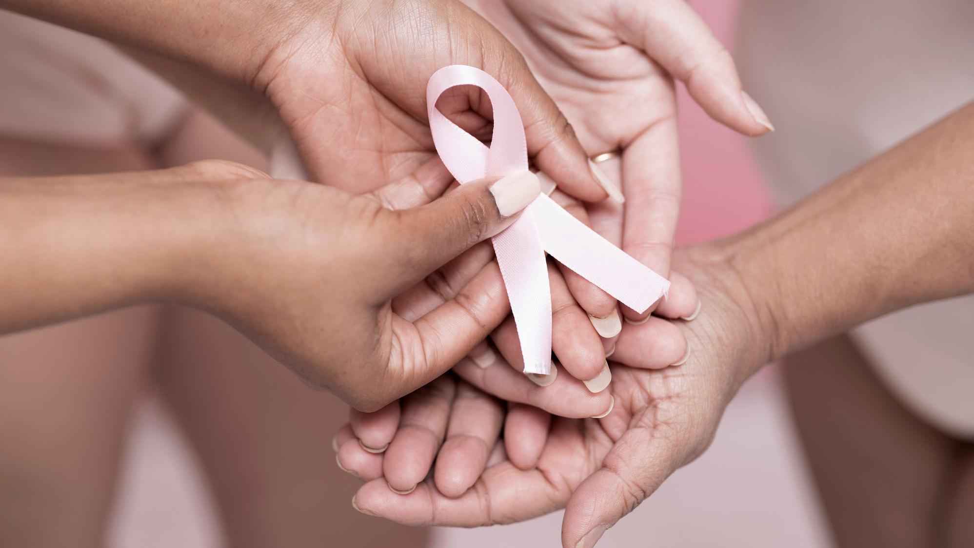 صورة مقربة لأيدي النساء وهن يحملن شريطاً وردياً للتوعية بسرطان الثدي 