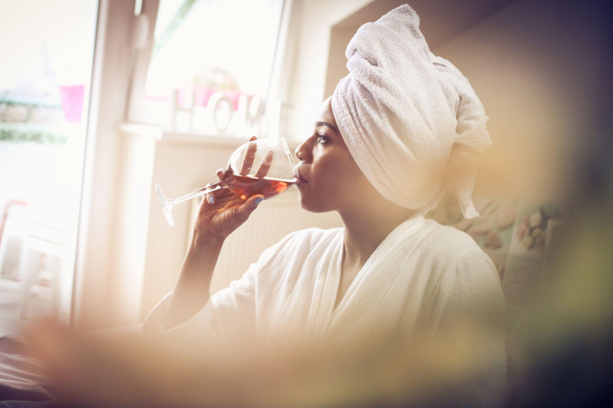 زنی در حال نوشیدن شراب در رختخواب