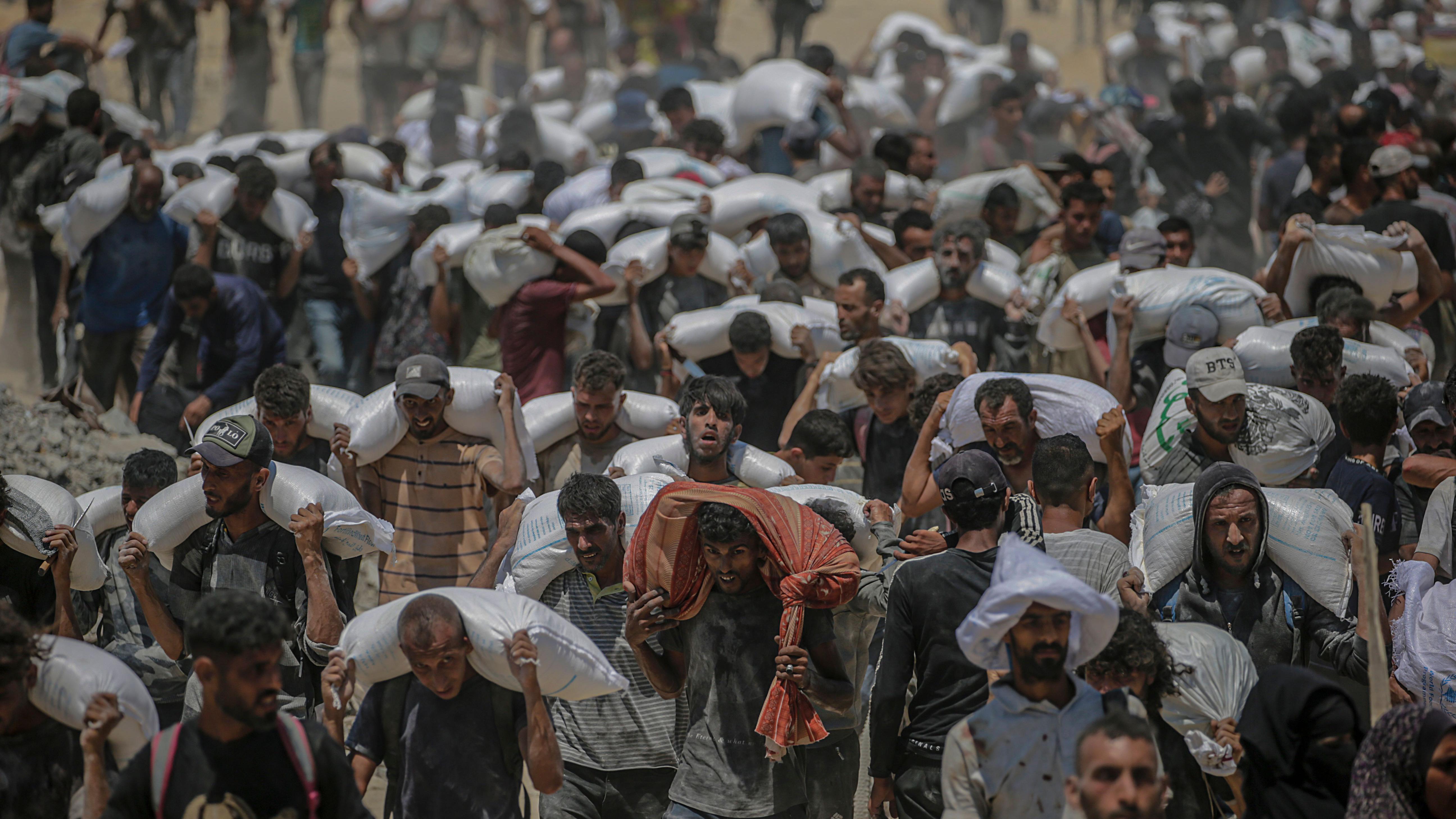 Palestinos deslocados internamente tentam pegar sacos de farinha de um caminhão de ajuda próximo a um ponto de distribuição de alimentos em Zikim, no norte da Faixa de Gaza, em 27 de julho de 2025.
