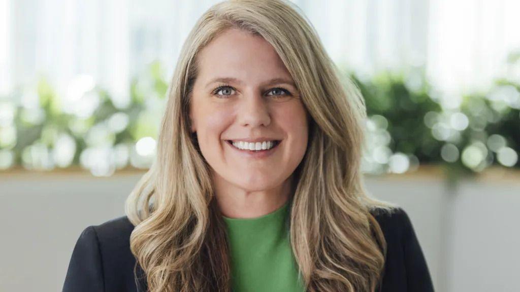 تريسي فرانكلين تبتسم وهي ترتدي سترة داكنة وقميصاً أخضر