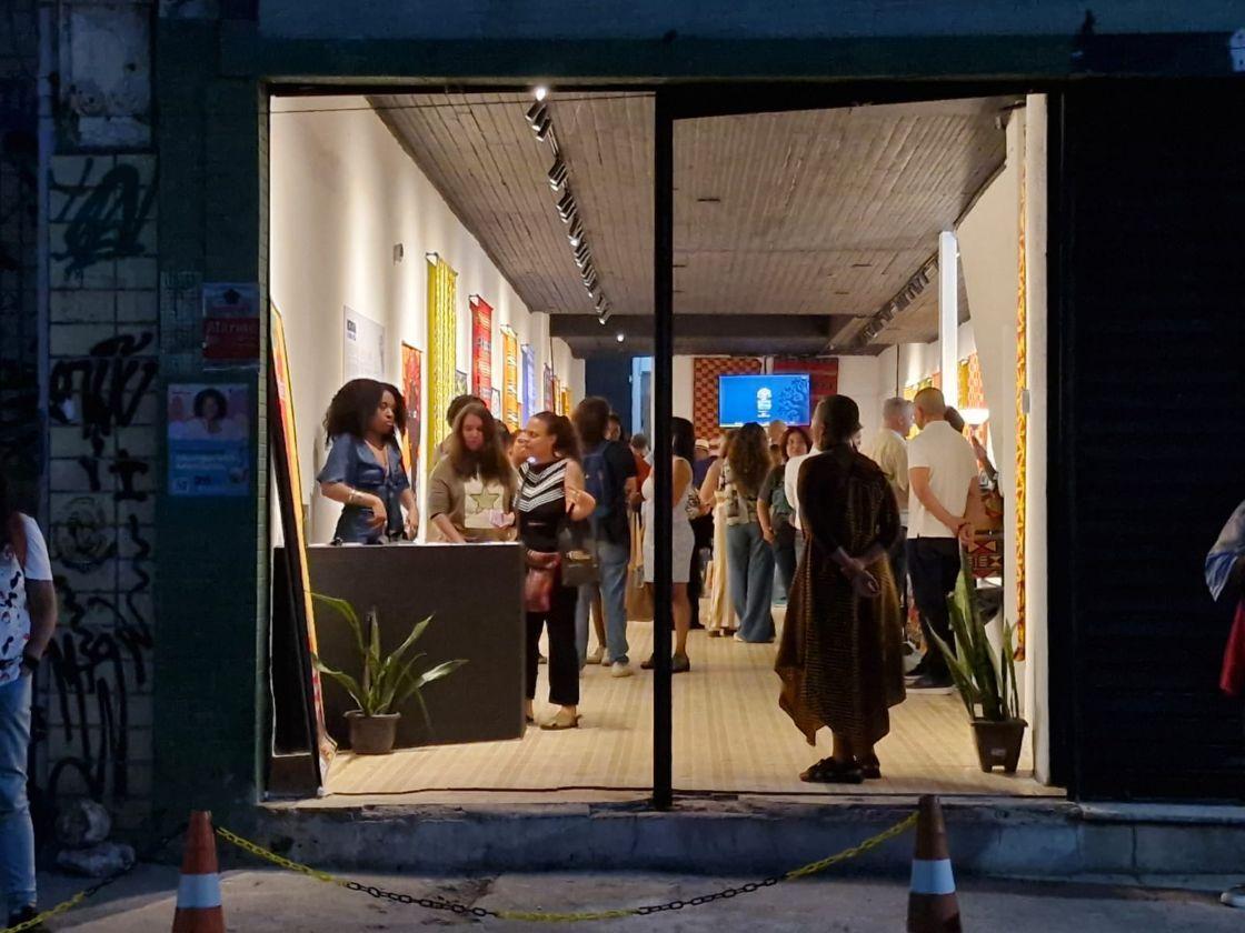 Imagem da entrada de um espa&ccedil;o com uma porta de vidro por onde se v&ecirc; v&aacute;rias pessoas