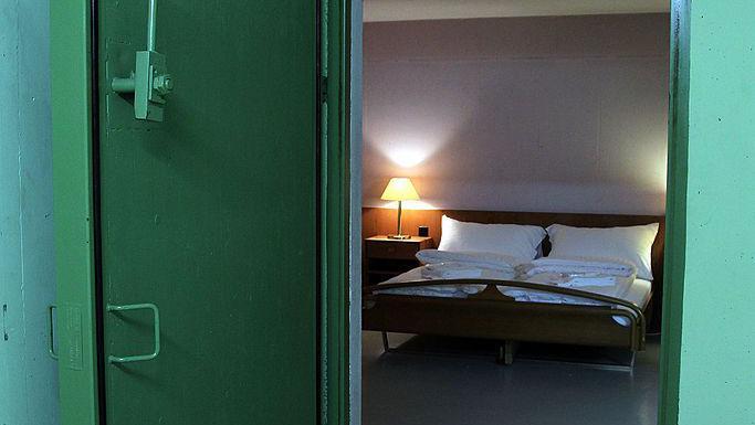 Una habitación de hotel dentro de un búnker con una puerta verde.