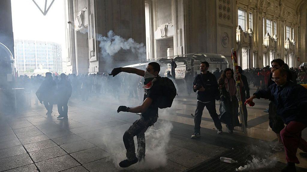 Un manifestamte lanza algo en medio de enfrentamientos con la policía antidisturbios en la estación de tren Milano Centrale, en Milán, el 22 de septiembre de 2025.