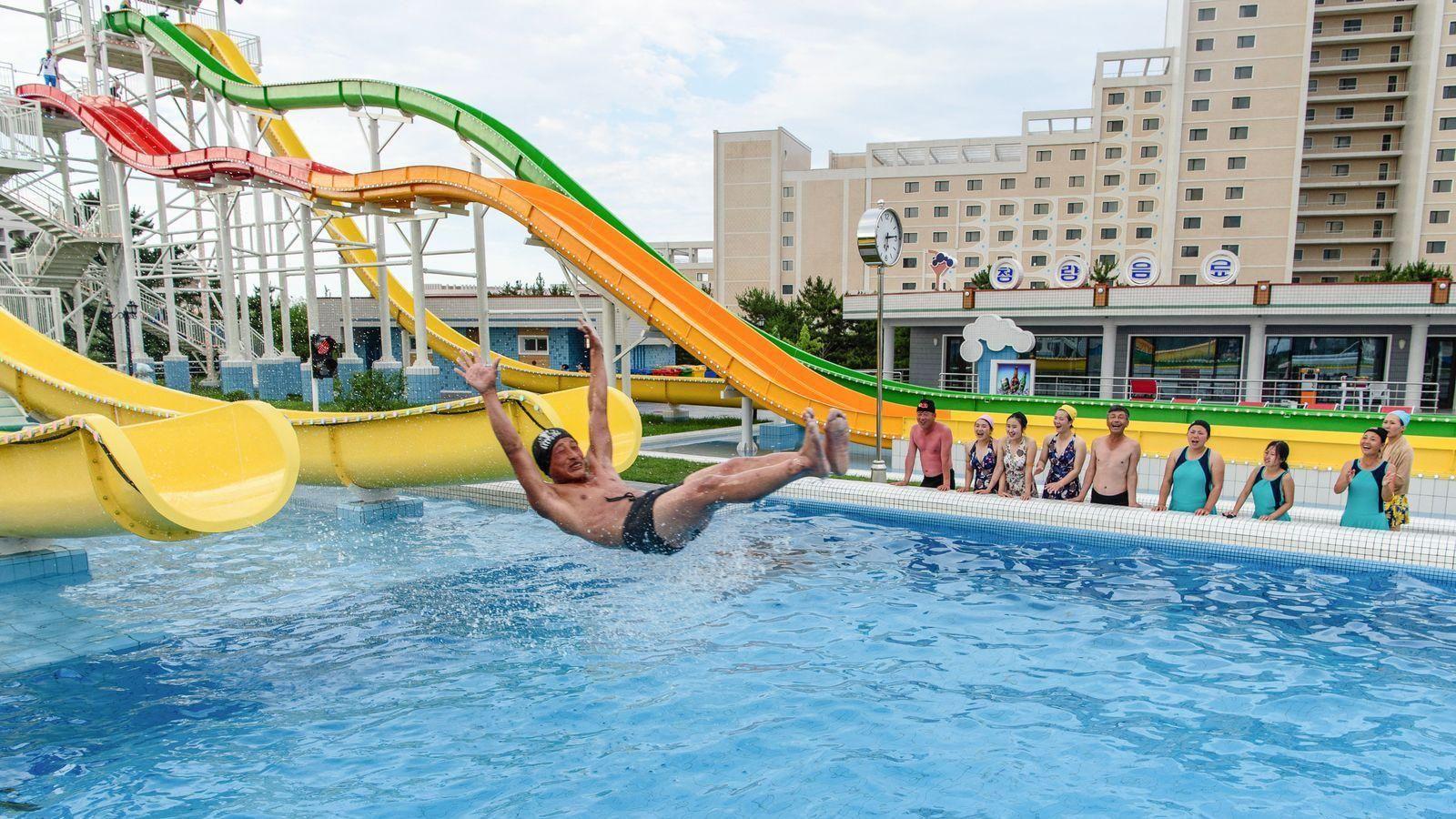 Turistas nacionales observan cómo un hombre usa un tobogán para nadar en una piscina en el parque acuático Myongsasimni en la zona turística costera Wonsan Kalma en Wonsan, provincia de Kangwon, Corea del Norte.