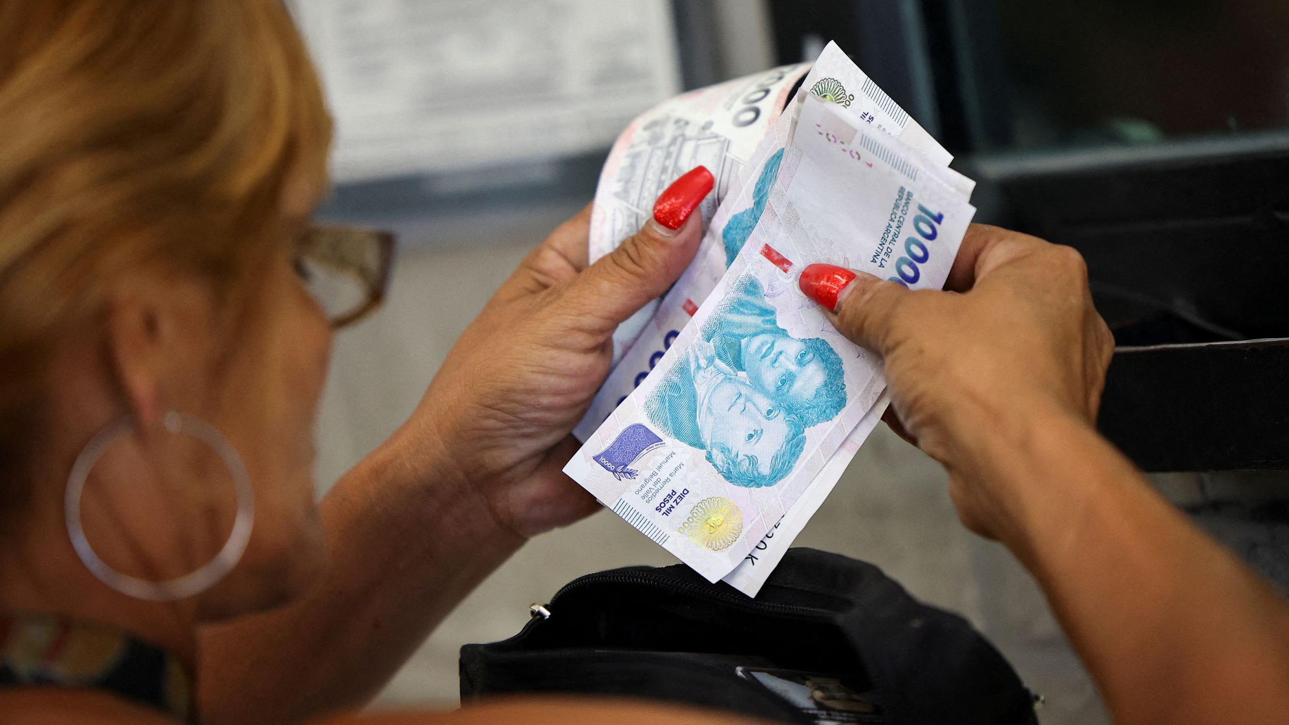 Una mujer cuenta pesos argentinos. 