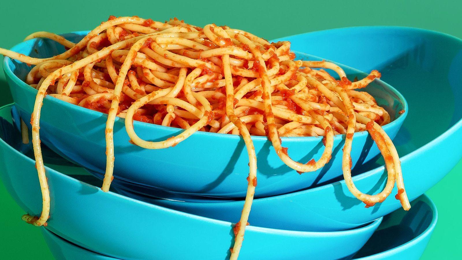 Varios platos amontonados y, sobre el último, un plato de pasta con tomate. 