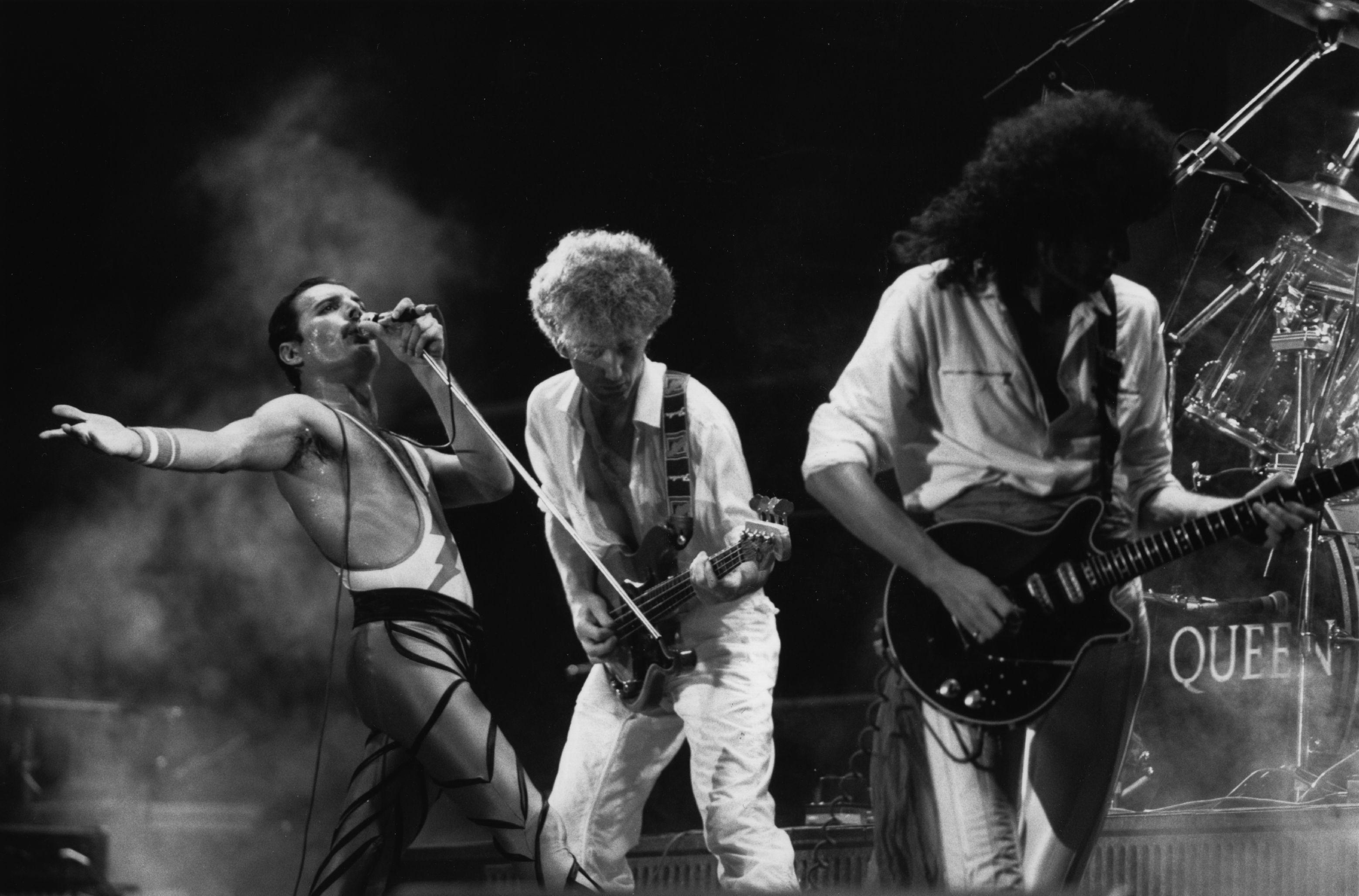 El grupo de rock británico Queen en concierto, de izquierda a derecha; Freddie Mercury (Frederick Bulsara, 1946 - 1991), John Deacon y Brian May.