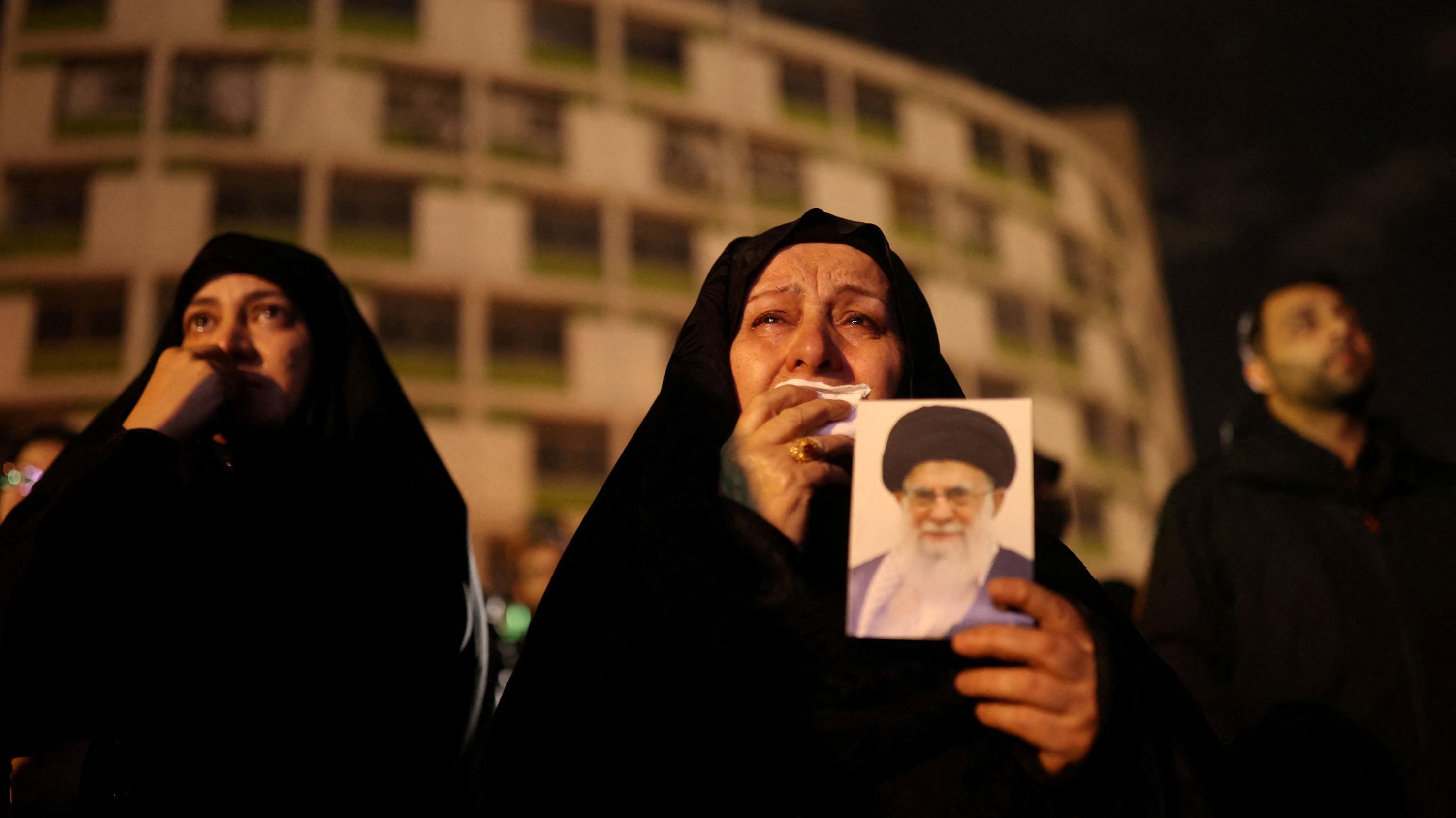 Uma mulher chorando e segurando a foto de Ali Khamenei