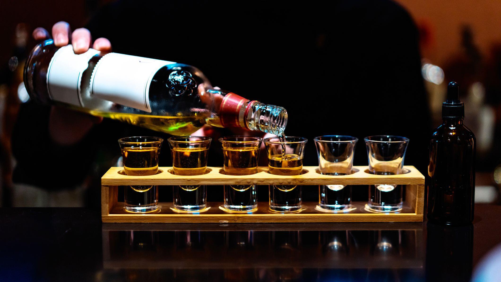 Pessoa servindo shots de bebida alcoólica destilada