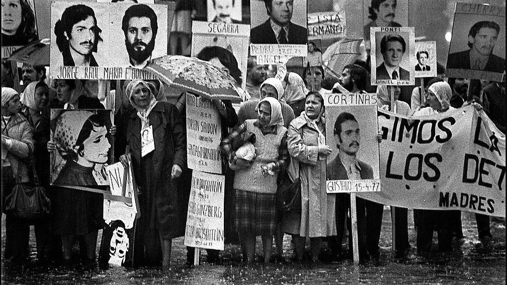 Mujeres con pañuelos blancos y carteles con fotos de personas desaparecidas