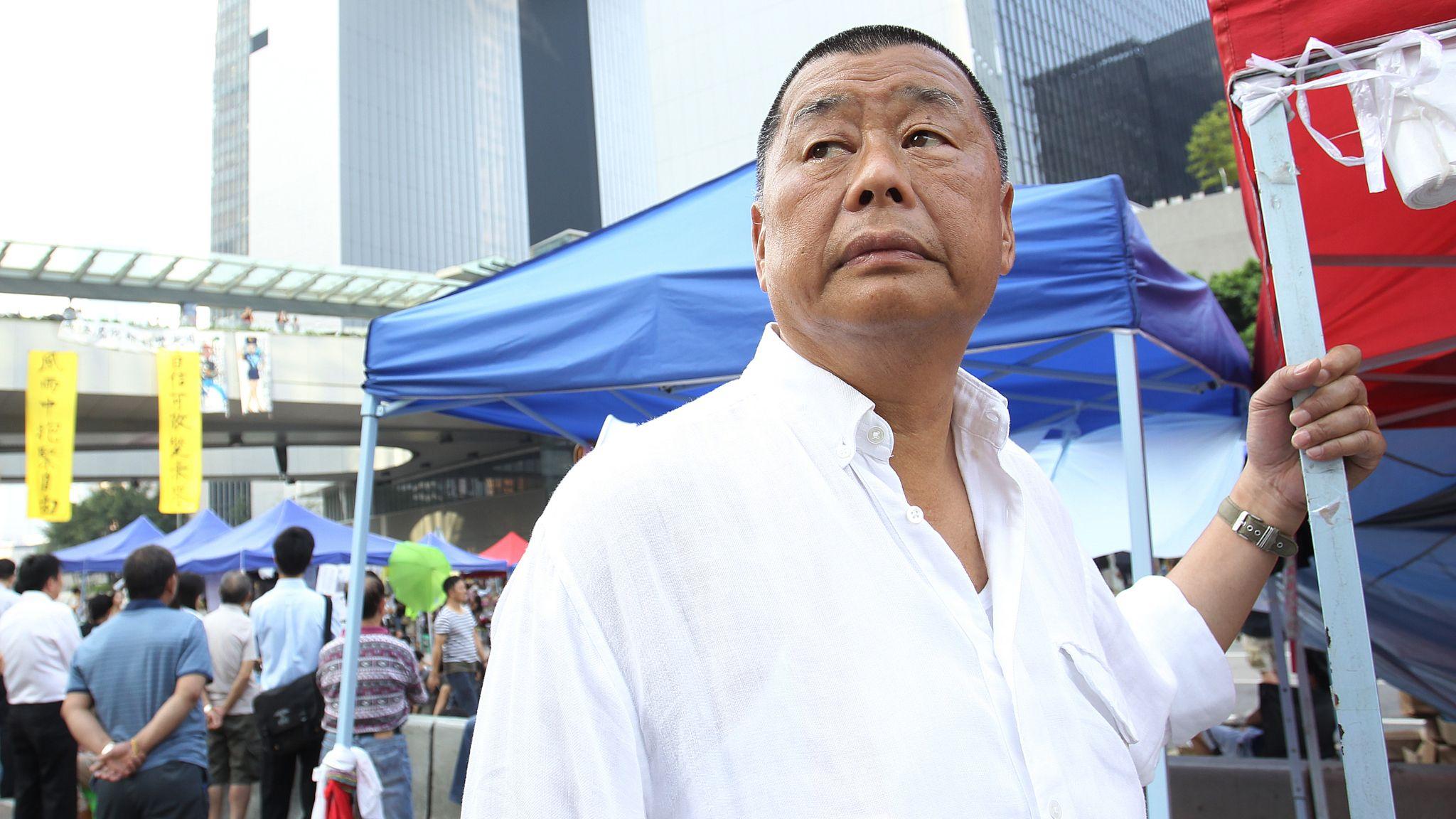 身穿白色襯衣的黎智英在香港金鐘夏愨道上的示威者佔領區內扶著一頂帳篷（7/10/2014）