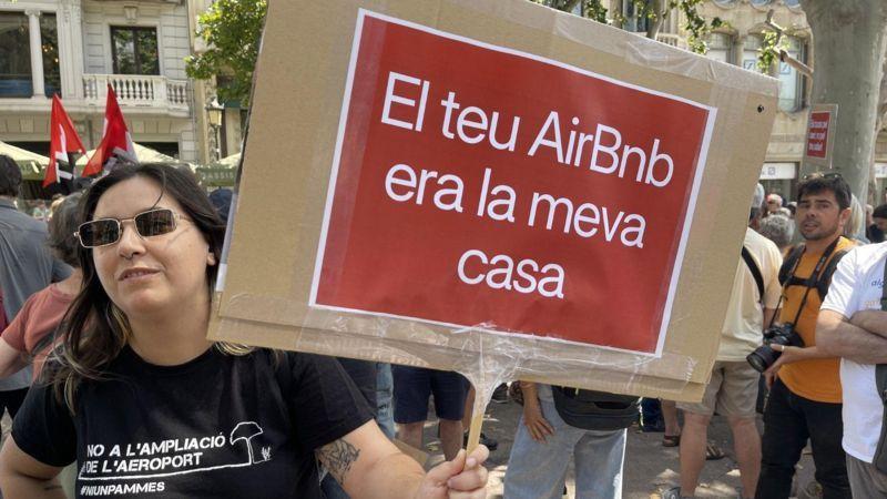 Mulher protesta nas ruas de Barcelona portando um cartaz que diz, em catalão,