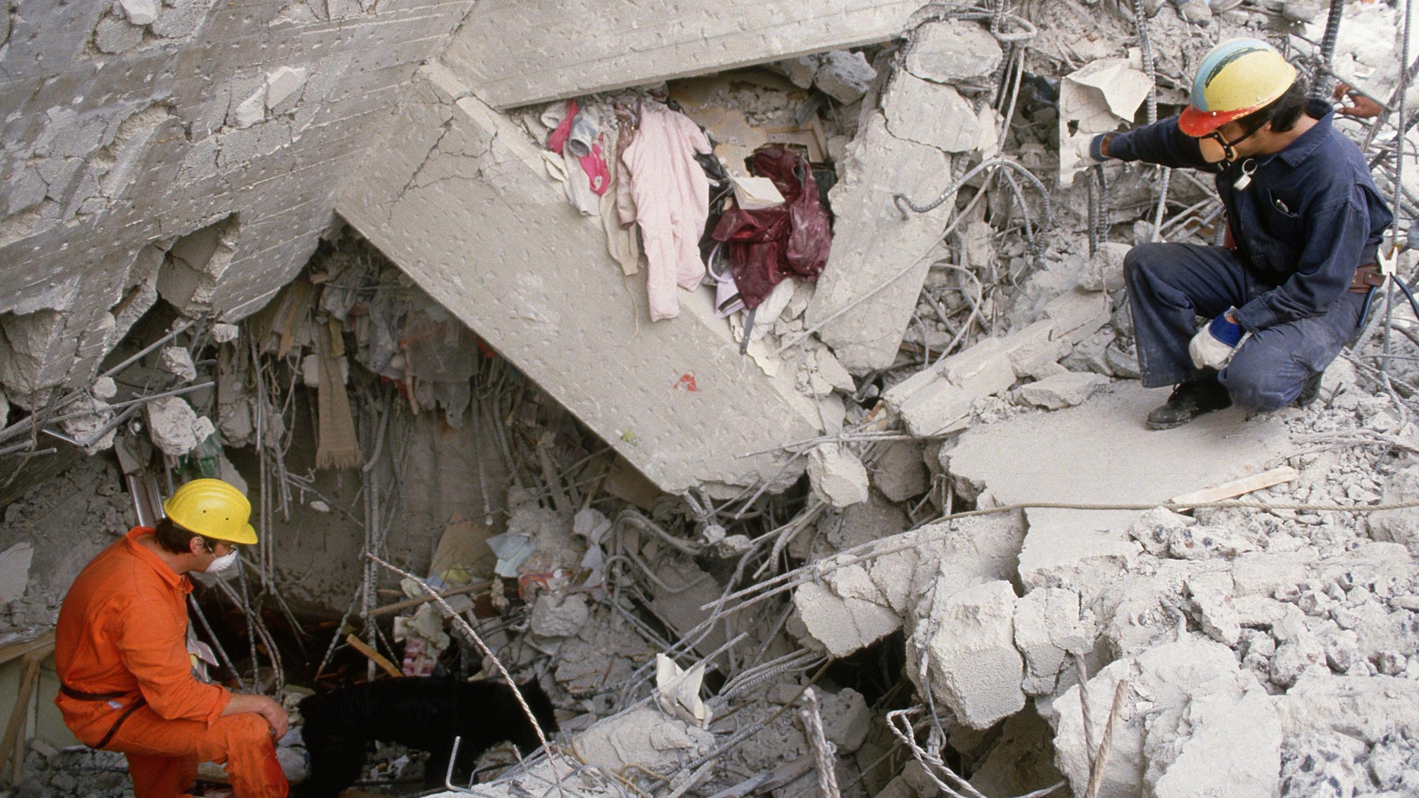 Dos rescatistas buscan entre escombros del terremoto de 1985