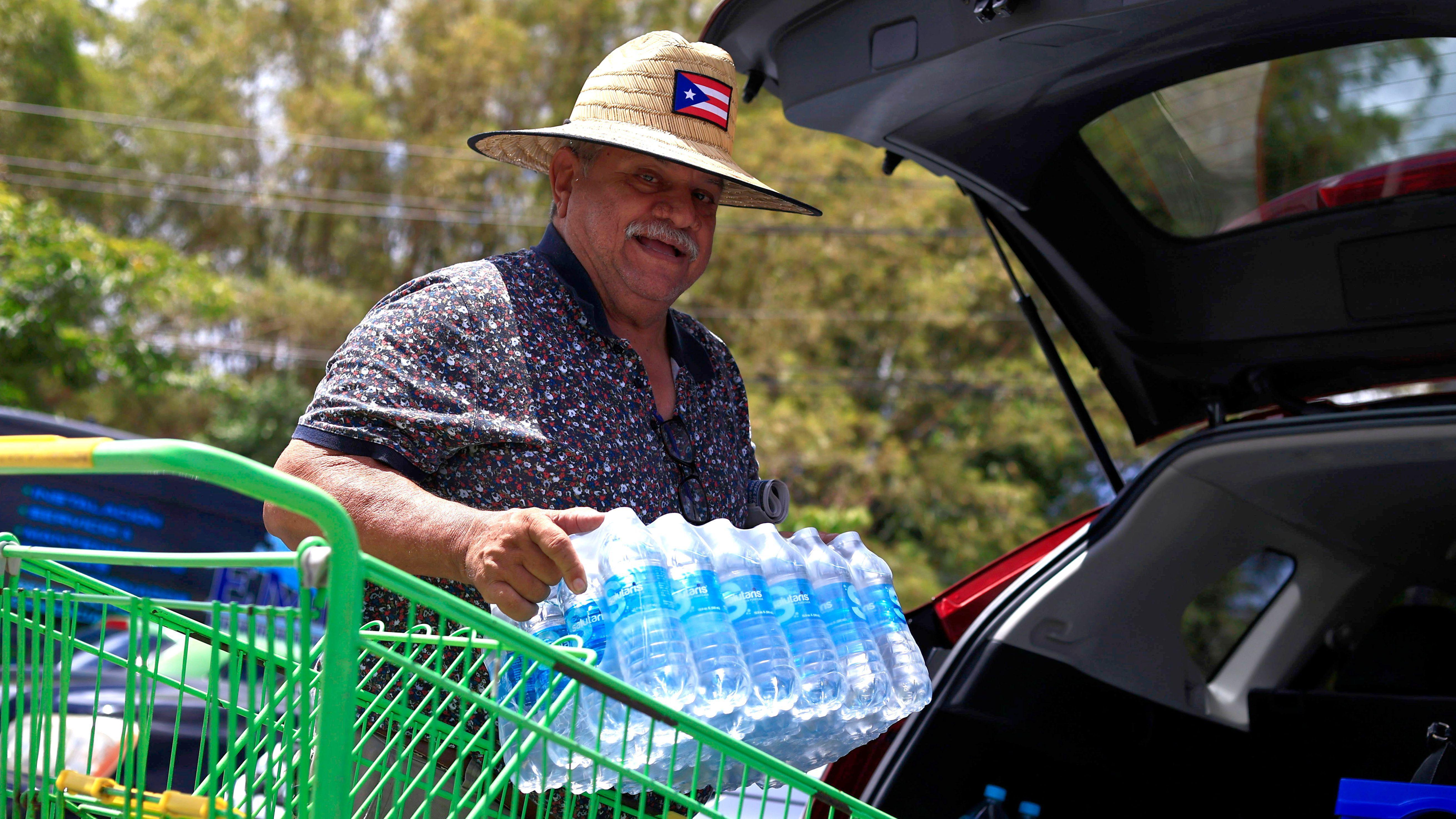 Un hombre carga botellas en el auto de agua mineral 