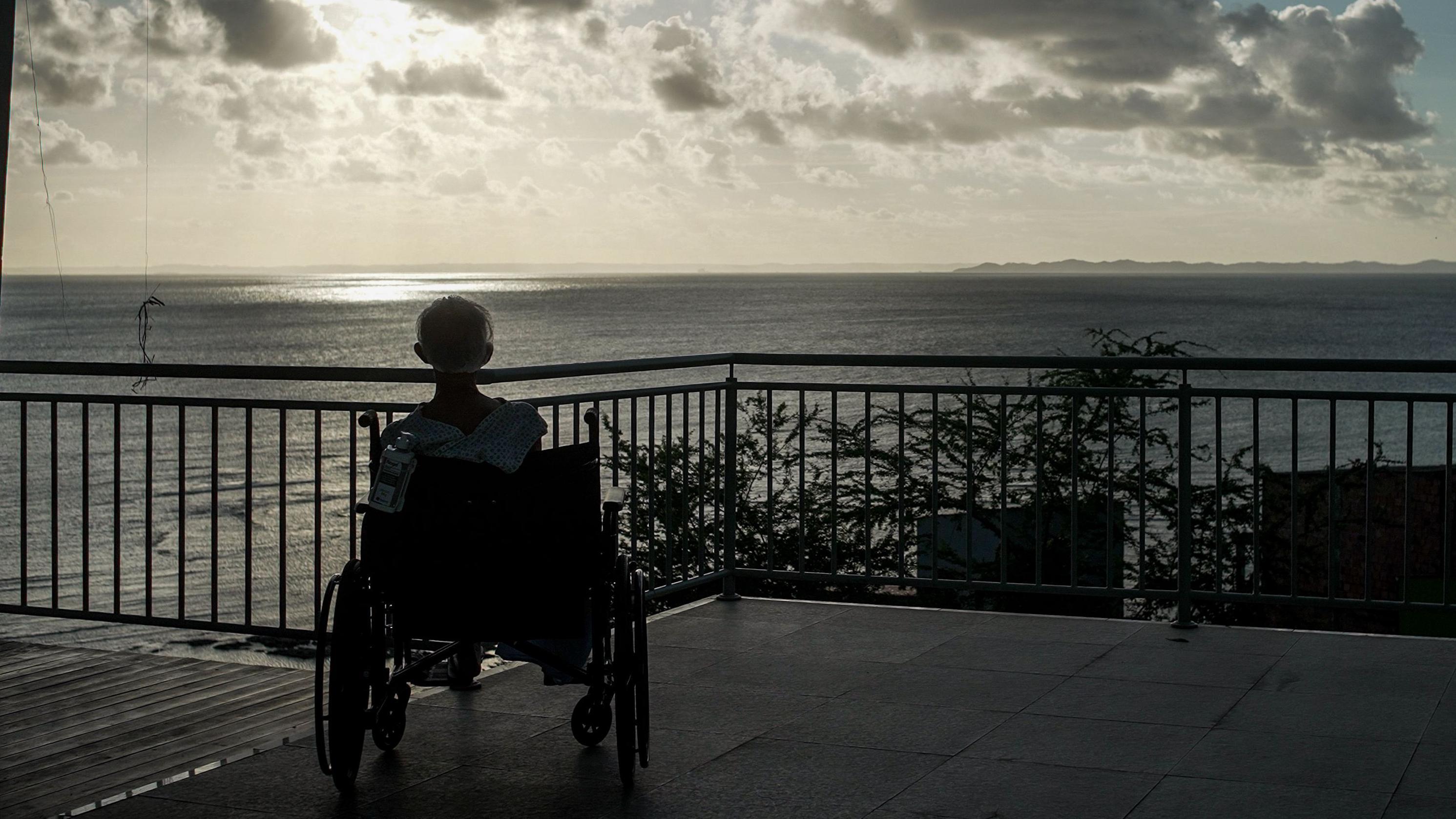 Un anciano en una silla de ruedas mira al mar