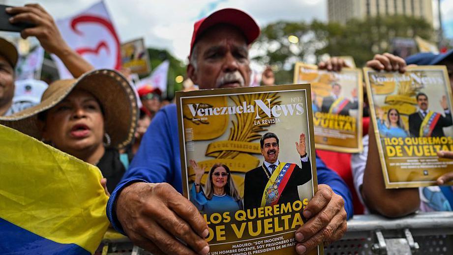 Un manifestante sostiene una portada de una revista con la foto de Maduro y de Cilia Flores en la que se lee: "Los queremos de vuelta"
