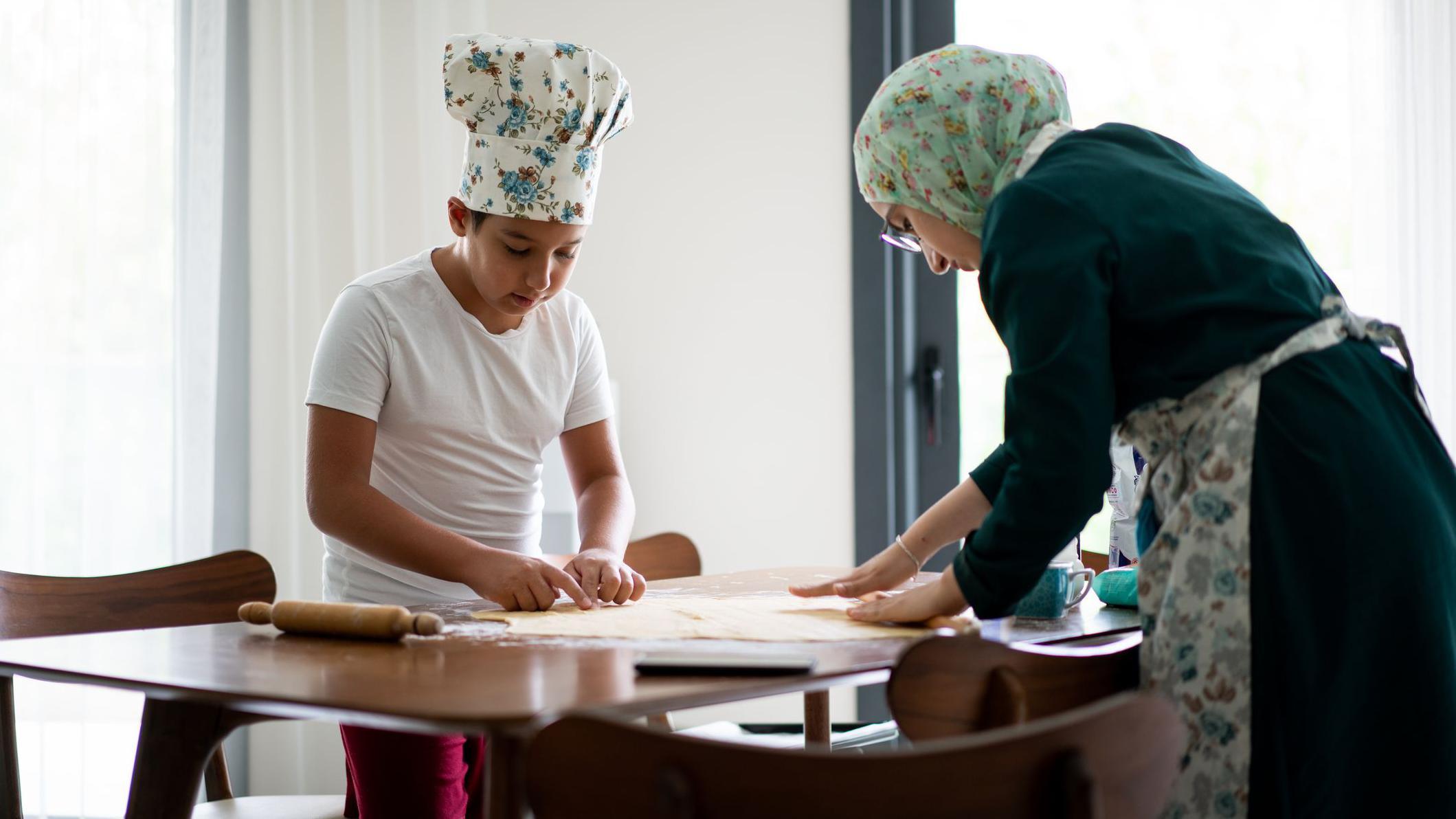 أم وطفلها يخبزان ويعدّان الطعام.